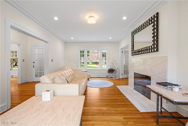 living area with a premium fireplace, recessed lighting, wood finished floors, and ornamental molding