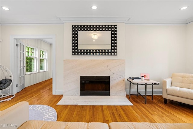 living room with wood finished floors, recessed lighting, a fireplace, crown molding, and baseboards