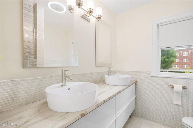 bathroom featuring tile walls, a wainscoted wall, and a sink