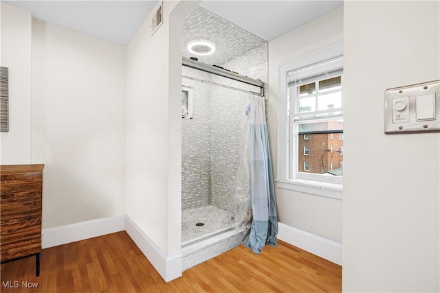 full bath featuring visible vents, a stall shower, baseboards, and wood finished floors