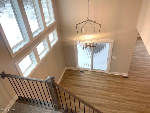 stairs featuring hardwood / wood-style flooring, a notable chandelier, and a towering ceiling