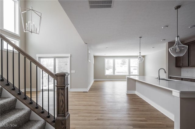 interior space with sink, light hardwood / wood-style flooring, an inviting chandelier, dark brown cabinetry, and decorative backsplash