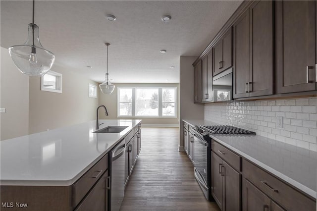 kitchen featuring pendant lighting, sink, appliances with stainless steel finishes, a kitchen island with sink, and backsplash