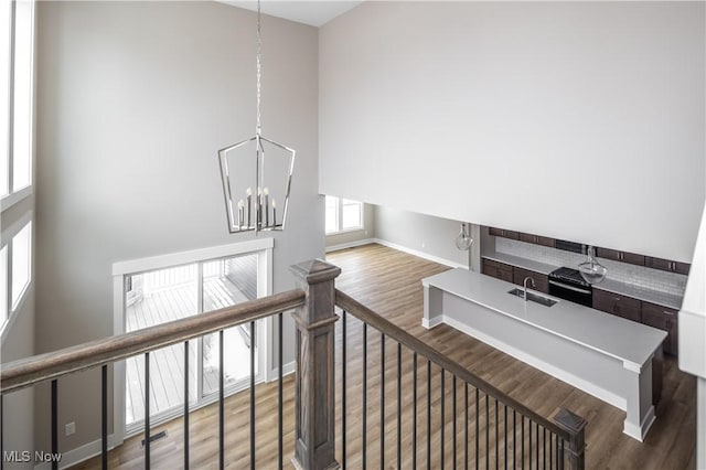 stairs featuring hardwood / wood-style flooring, sink, and a chandelier