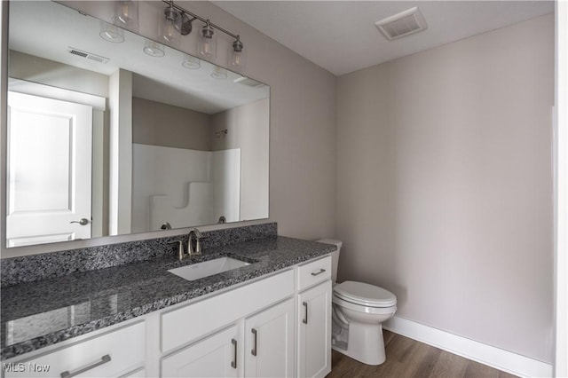 bathroom featuring wood-type flooring, toilet, vanity, and walk in shower