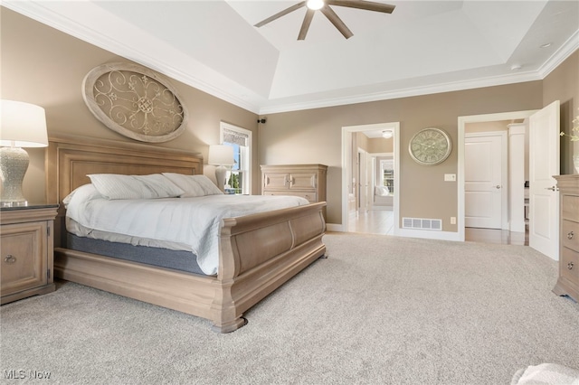 bedroom with a tray ceiling, ornamental molding, ceiling fan, and light carpet