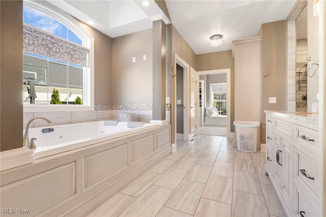 full bathroom with a bath, vanity, and baseboards