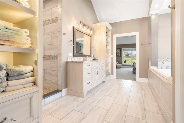 bathroom featuring vaulted ceiling, a garden tub, vanity, and baseboards