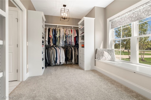 spacious closet featuring a chandelier and light colored carpet