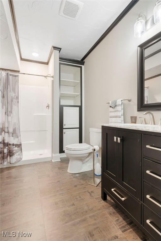 bathroom with curtained shower, vanity, crown molding, wood-type flooring, and toilet