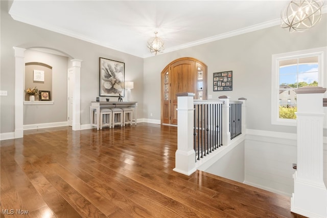 interior space with arched walkways, decorative columns, ornamental molding, wood finished floors, and baseboards