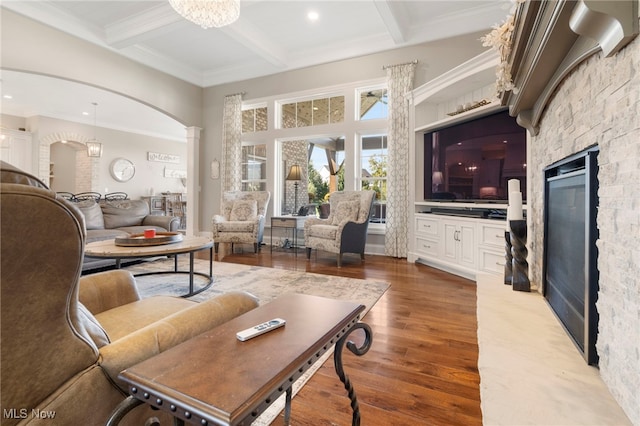 living room featuring arched walkways, beam ceiling, ornate columns, and wood finished floors