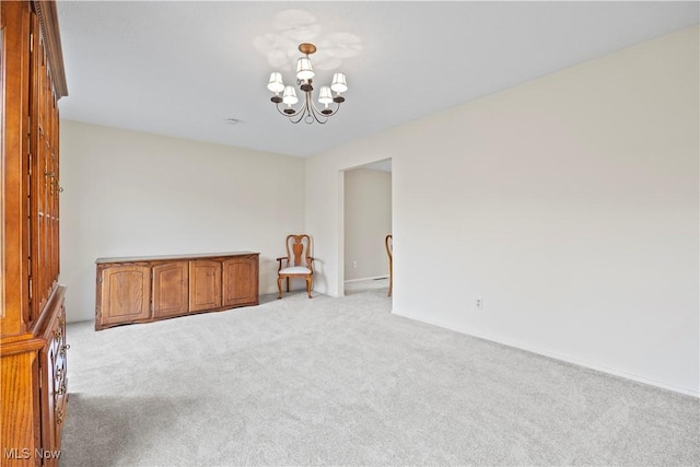 carpeted empty room with an inviting chandelier