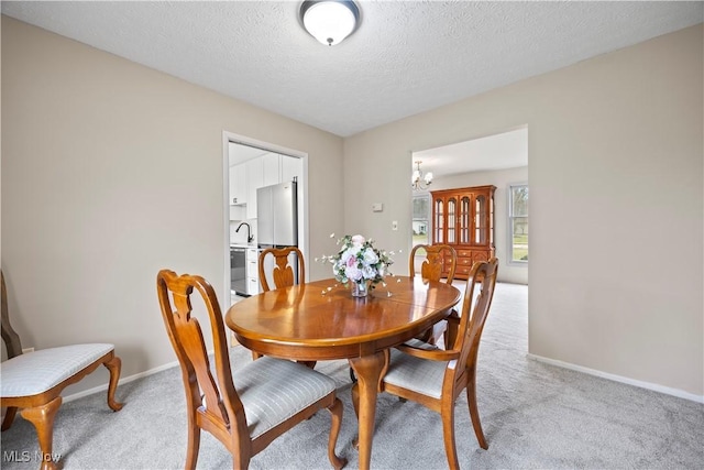 carpeted dining area with sink, a textured ceiling, and a chandelier