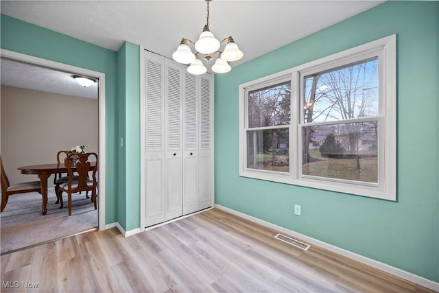 unfurnished dining area with a chandelier and light wood-type flooring