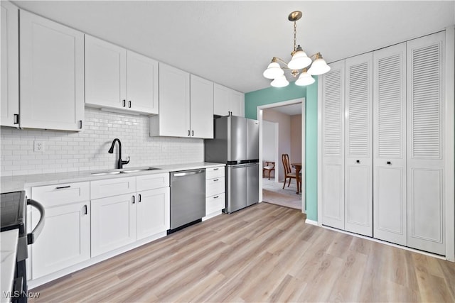 kitchen featuring appliances with stainless steel finishes, tasteful backsplash, sink, white cabinets, and hanging light fixtures