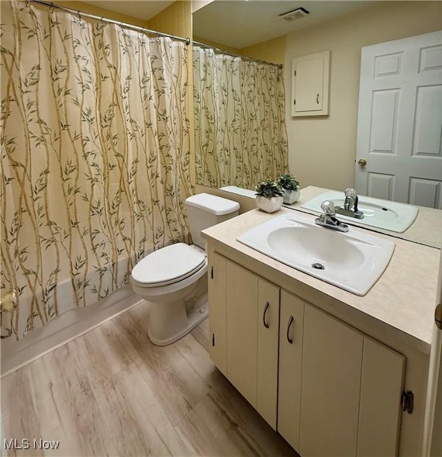 full bathroom with vanity, wood-type flooring, shower / bath combo, and toilet