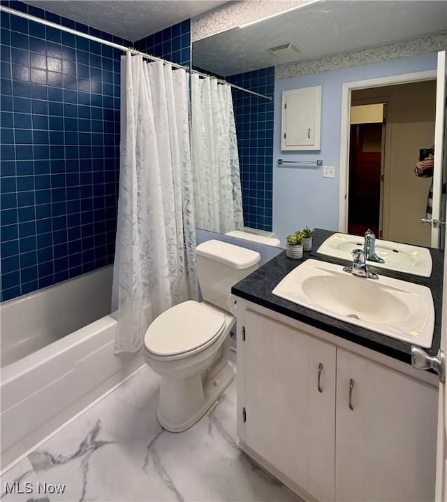 full bathroom featuring vanity, toilet, a textured ceiling, and shower / bath combo with shower curtain