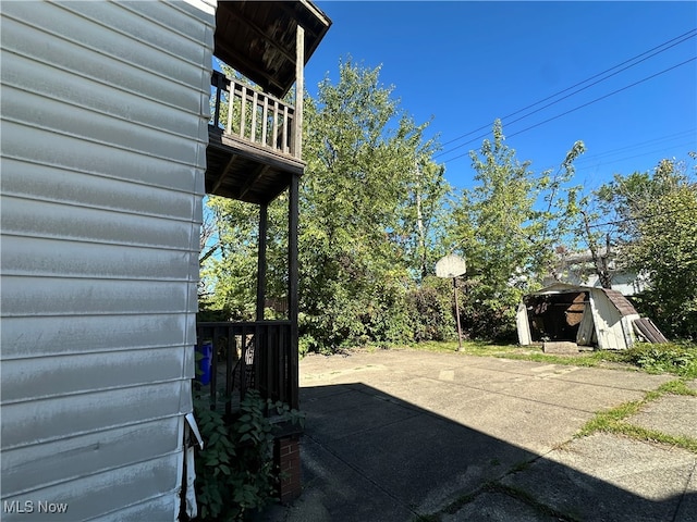 view of patio with a storage unit and a balcony