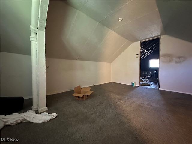 bonus room featuring lofted ceiling and dark colored carpet