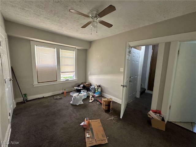 interior space with ceiling fan, a textured ceiling, and dark colored carpet