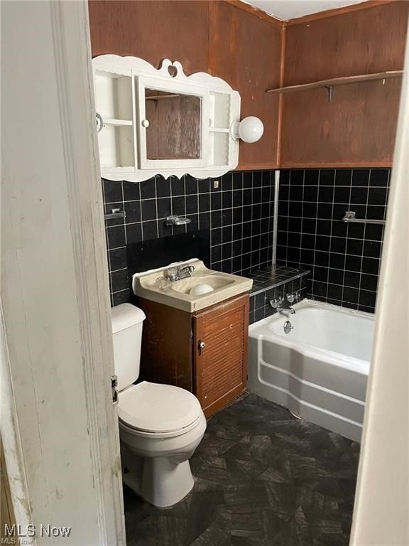 bathroom featuring vanity, tile walls, toilet, and a bath