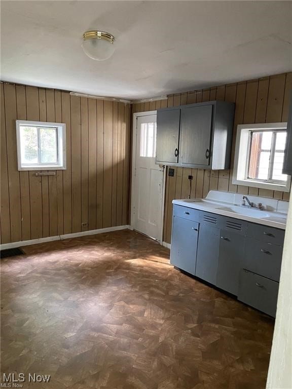 kitchen with gray cabinets, sink, and wooden walls