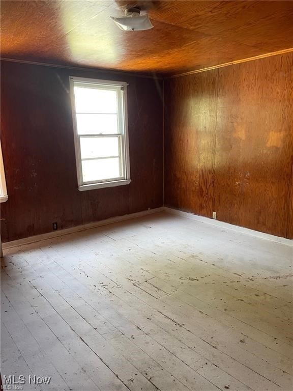 empty room with wood walls and light hardwood / wood-style flooring