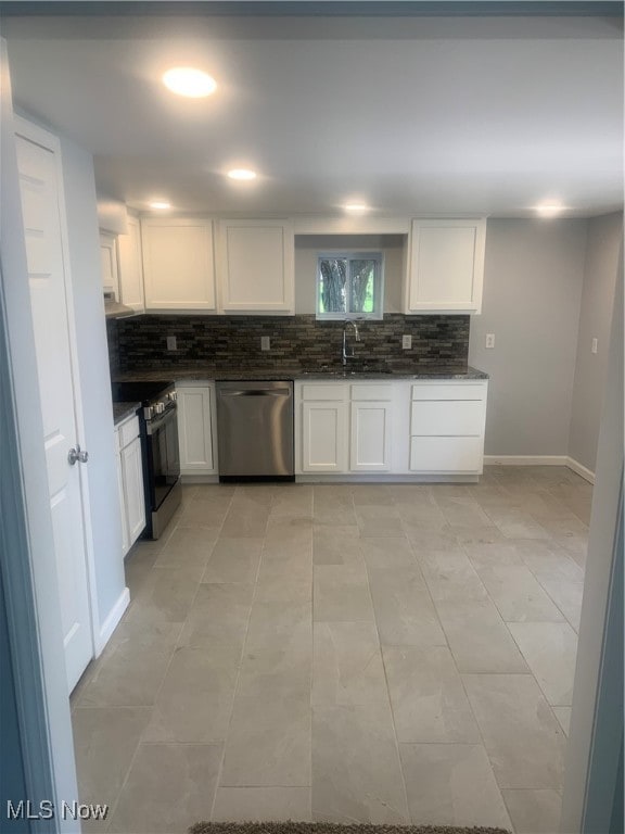 kitchen with decorative backsplash, white cabinets, light tile patterned floors, stainless steel appliances, and sink