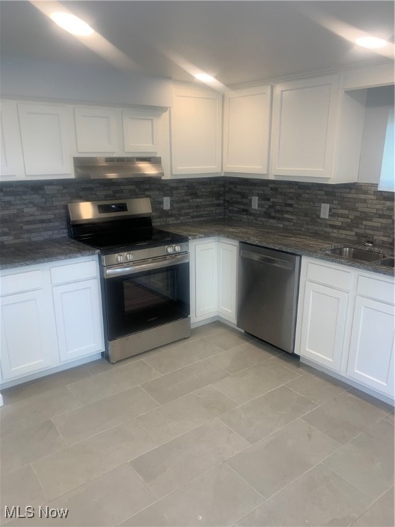 kitchen featuring appliances with stainless steel finishes, dark stone countertops, white cabinets, backsplash, and sink