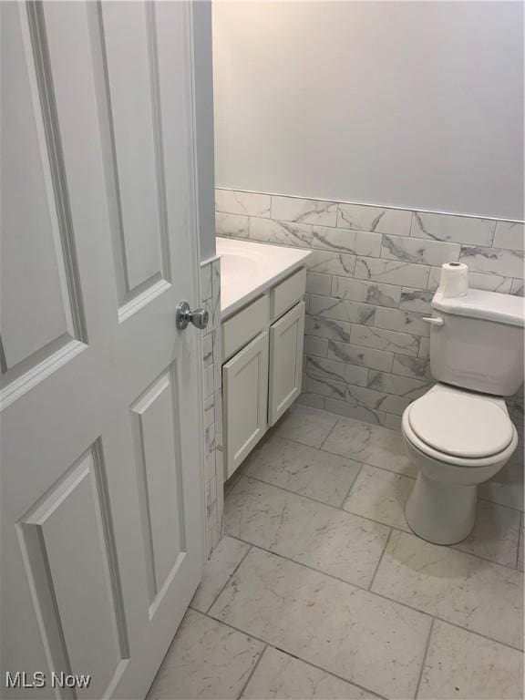 30436 State Route 172, East Rochester, OH 44625 - bathroom featuring vanity, toilet, wainscoting, marble finish flooring, and tile walls