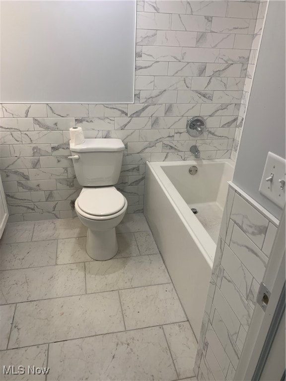 bathroom with a tub to relax in, toilet, and tile walls