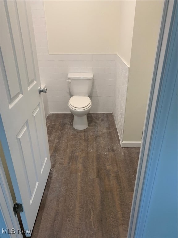 bathroom with wood-type flooring, tile walls, and toilet