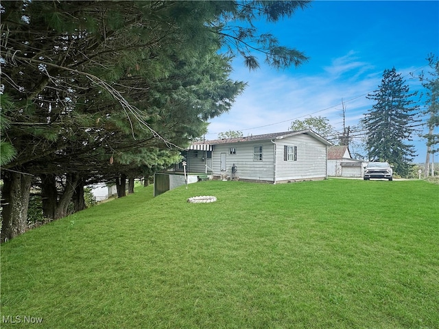 rear view of property with a lawn and an outdoor fire pit