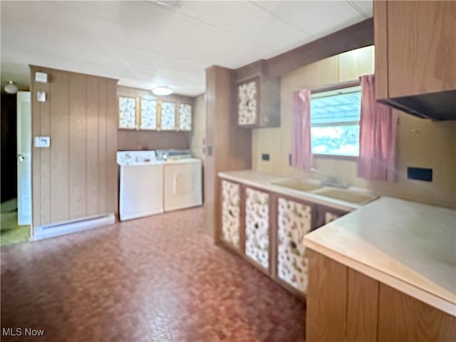 kitchen with baseboard heating, wood walls, and washing machine and clothes dryer