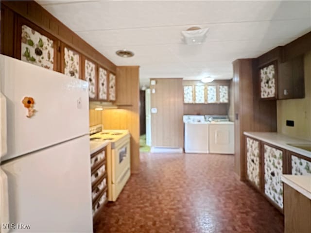 kitchen featuring white appliances, wooden walls, and washer and dryer