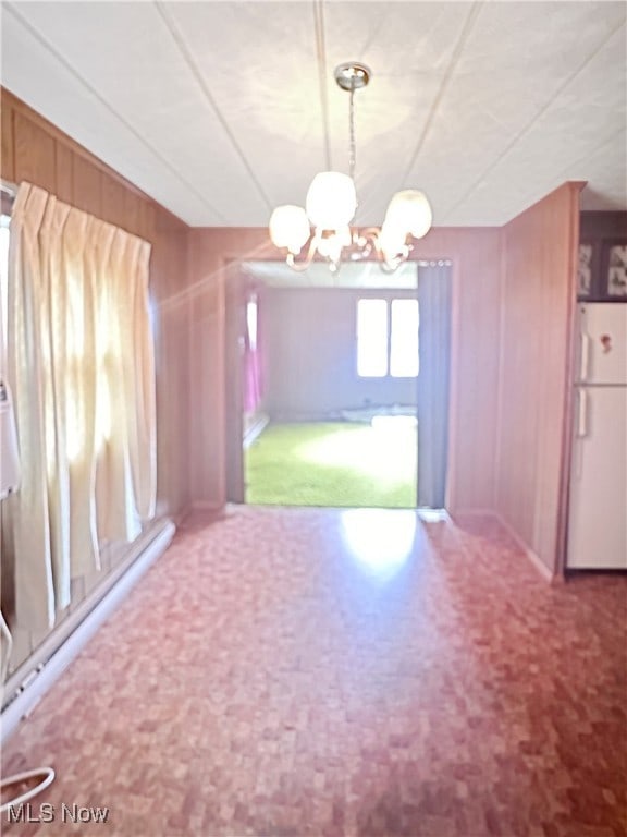 unfurnished dining area with an inviting chandelier, wooden walls, and carpet