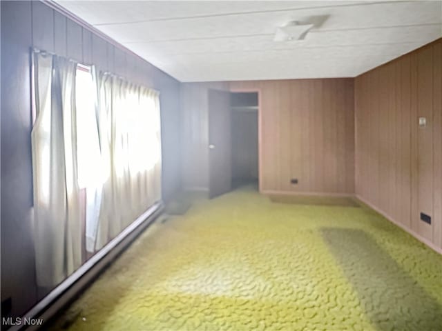 carpeted spare room featuring wood walls