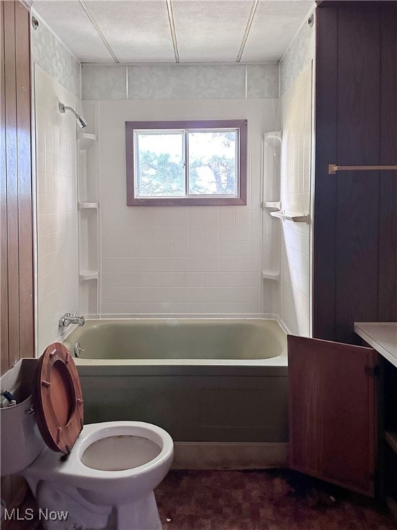 bathroom featuring toilet and tiled shower / bath