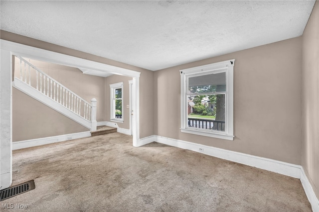 spare room featuring a textured ceiling and carpet flooring