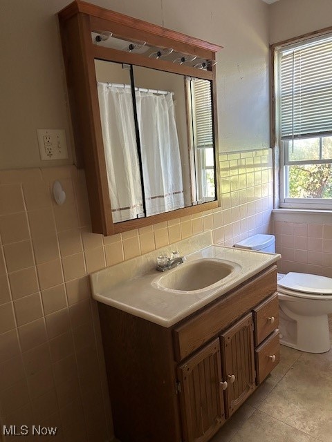 bathroom with tile walls, vanity, toilet, and tile patterned floors