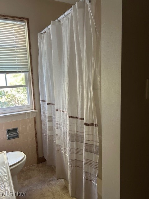 bathroom featuring tile walls, tile patterned flooring, toilet, and a shower with curtain