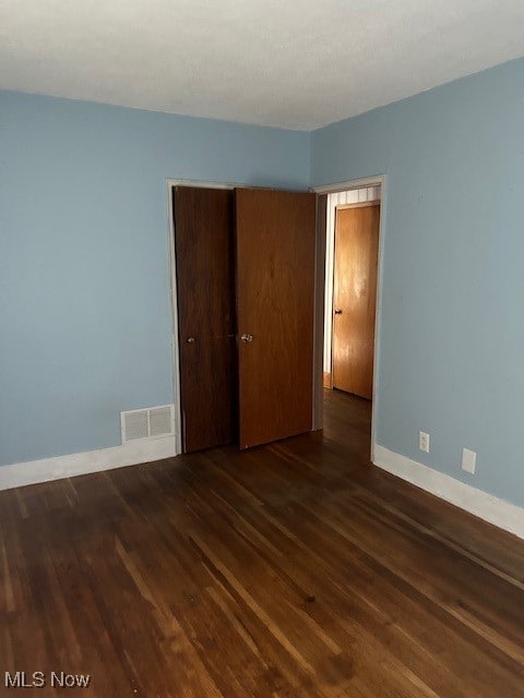 unfurnished bedroom with a closet and dark hardwood / wood-style flooring