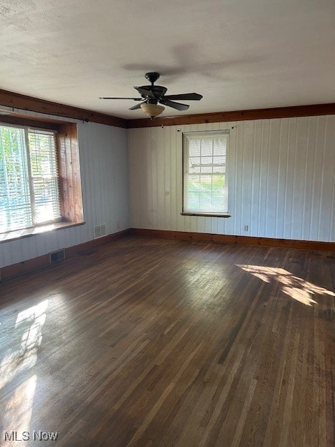 unfurnished room with a wealth of natural light, ceiling fan, and dark wood-type flooring