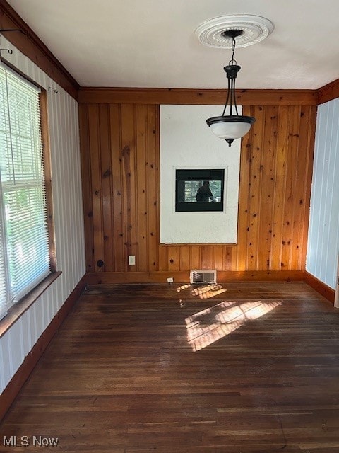 unfurnished dining area featuring wood walls and dark hardwood / wood-style flooring