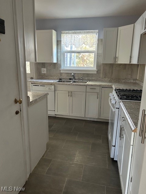 kitchen with light stone counters, white cabinets, sink, white appliances, and decorative backsplash