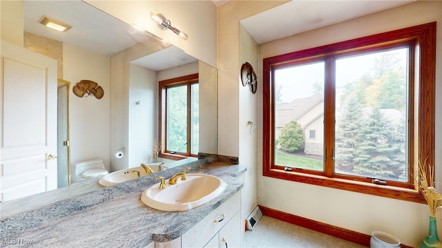 bathroom featuring a healthy amount of sunlight, vanity, and toilet