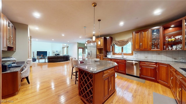 kitchen with light hardwood / wood-style flooring, dark stone countertops, a center island, and appliances with stainless steel finishes