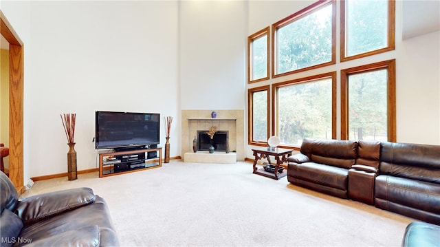 living room featuring carpet floors, a towering ceiling, and a tiled fireplace