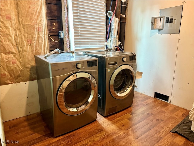 laundry area featuring electric panel, light wood-type flooring, and washer and dryer